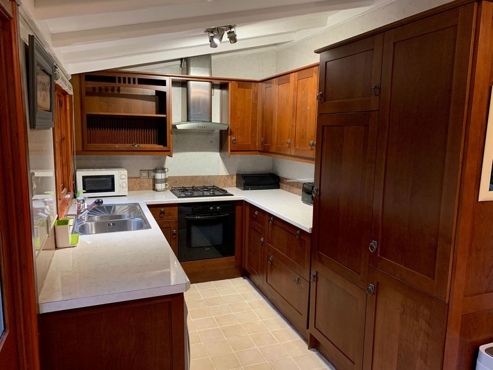A kitchen with wooden cabinets and appliances at The Hermitage in Penrith