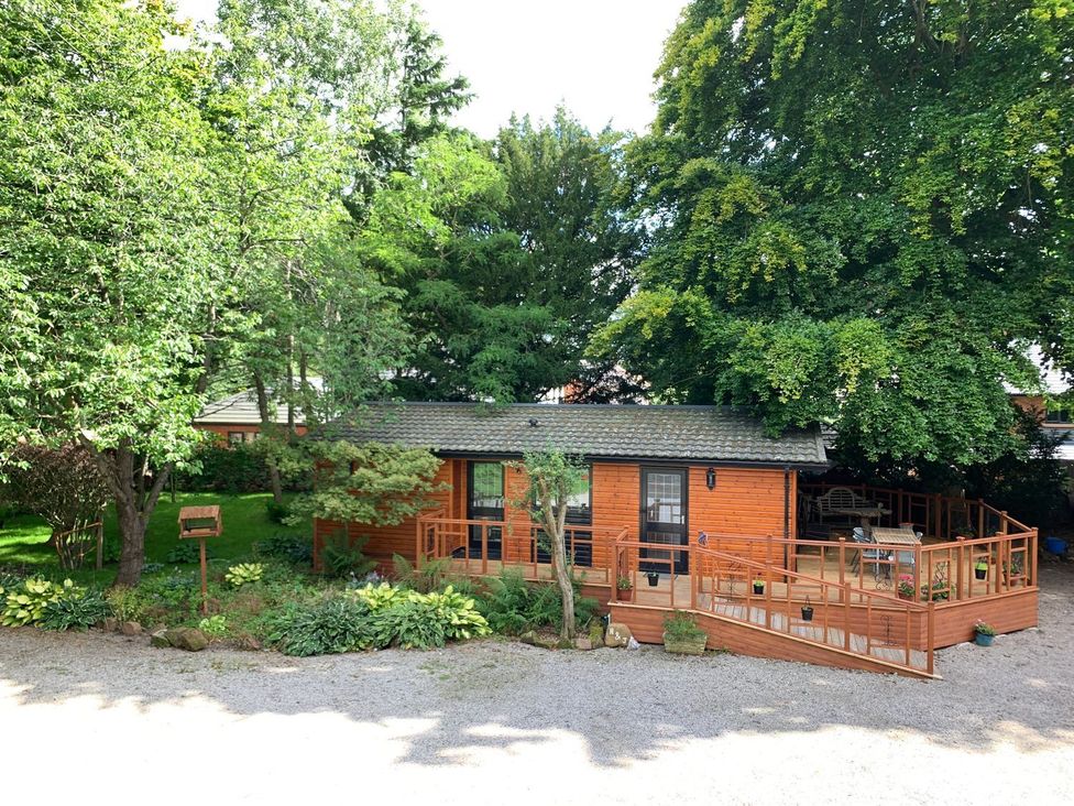 A house with a wooden deck surrounded by trees at The Hermitage in Penrith