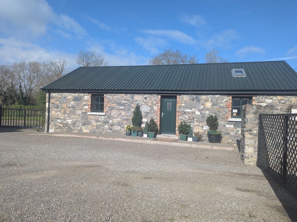 A stone building with a green door and potted plants at The Stable Swords, County Dublin