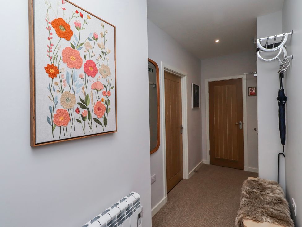 A hallway with flower wall art and doors at Amber Rose in Berwick-Upon-Tweed