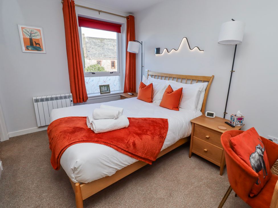 A bedroom with a bed and orange accents at Amber Rose in Berwick-Upon-Tweed