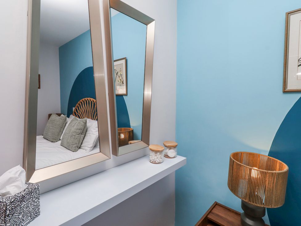 A bedroom with a bed and mirrors at Amber Rose in Berwick-Upon-Tweed