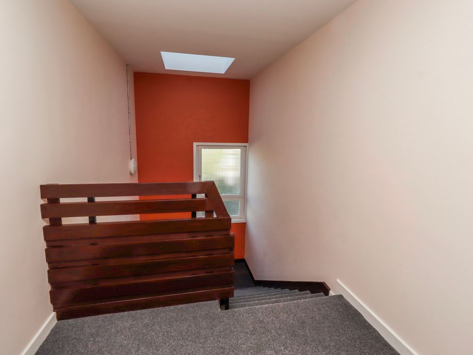 A staircase with a wooden railing and window at Amber Rose in Berwick-Upon-Tweed