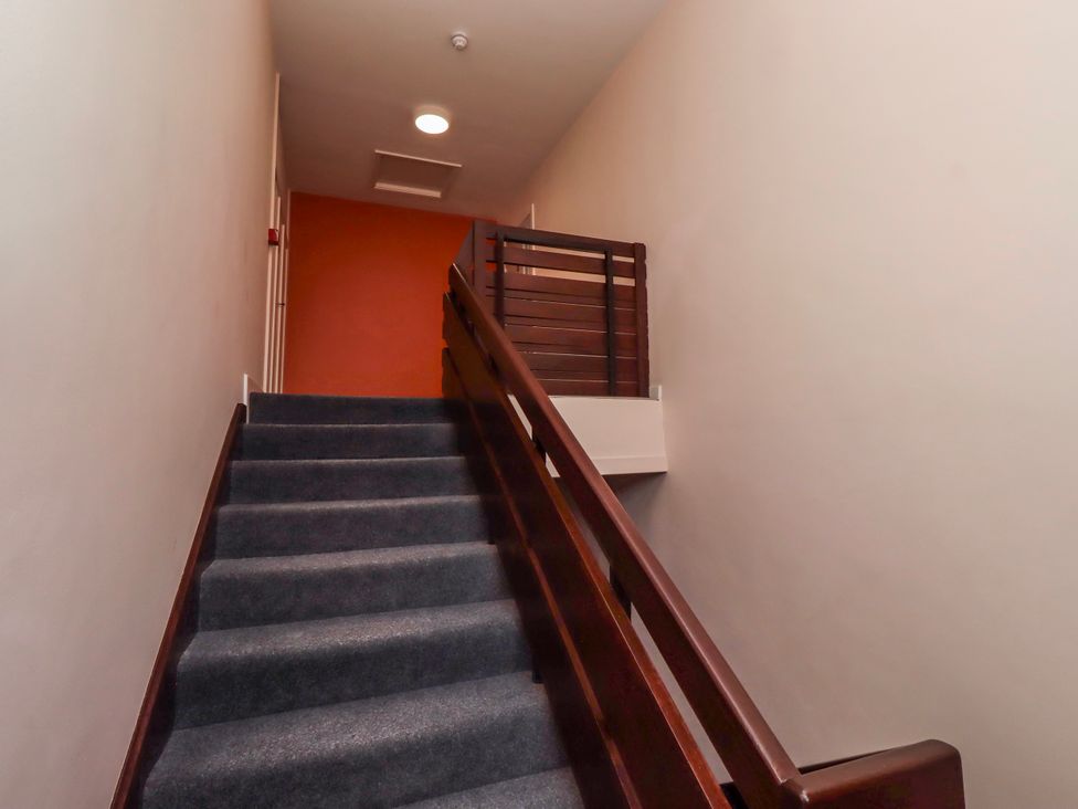 A staircase with wooden handrail and light in the hallway at Amber Rose Berwick-Upon-Tweed