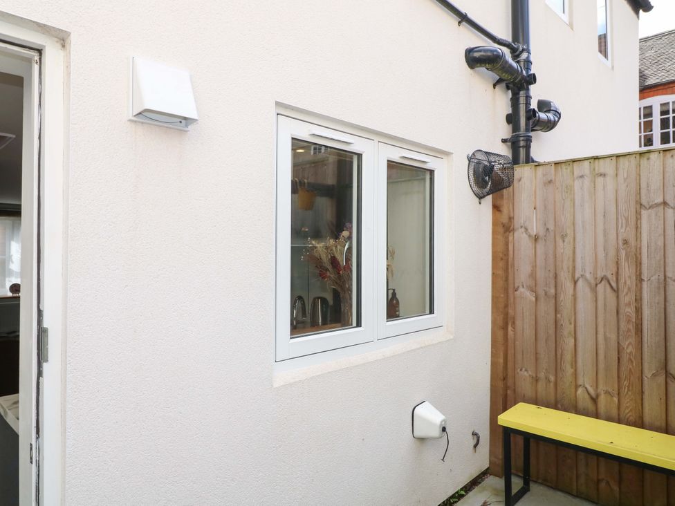 An outdoor area with a window and a yellow bench at Jolly Cottage in Derby