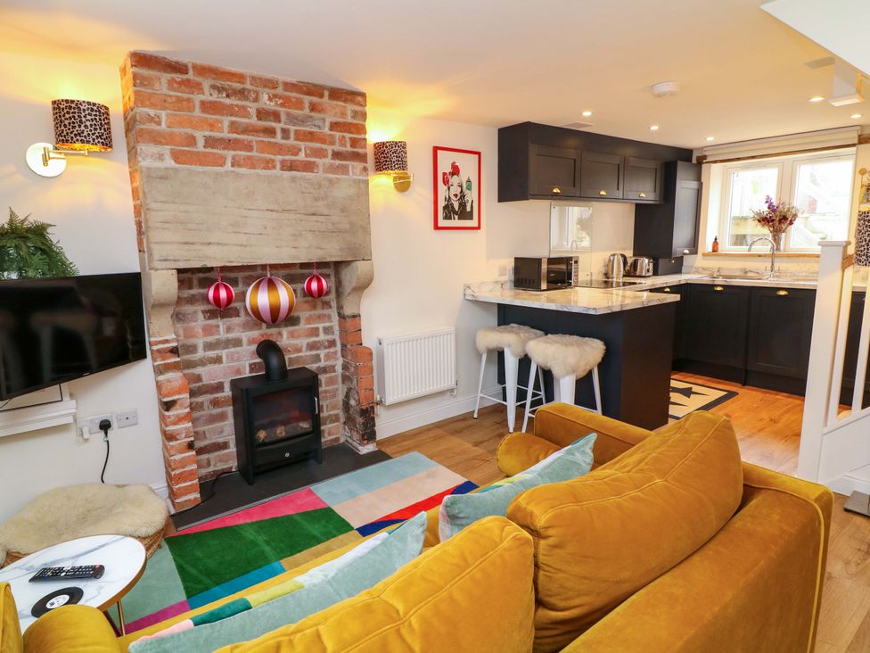 A living room with a fireplace and kitchen area at Jolly Cottage in Derby