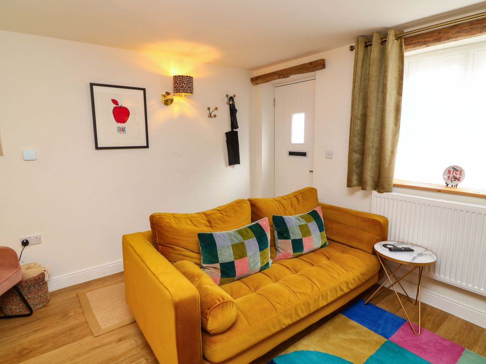A living room with a yellow sofa and colorful pillows at Jolly Cottage in Derby