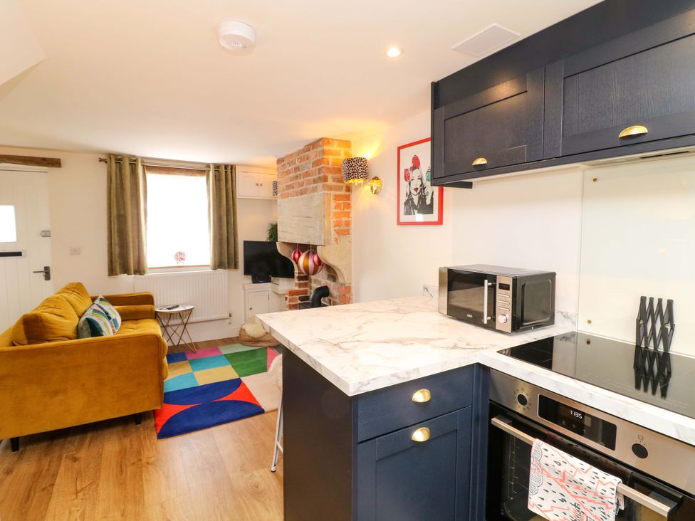 A living room and kitchen area with a sofa and appliances at Jolly Cottage in Derby