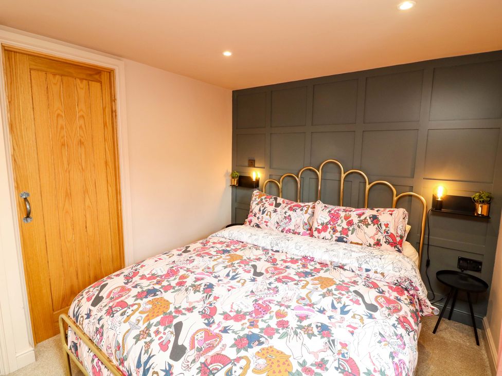 A bedroom with a bed and bedside shelves at Jolly Cottage in Derby