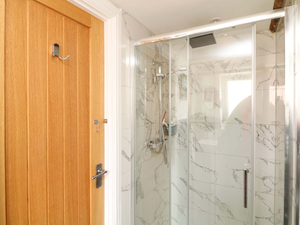 A bathroom with a shower and a wooden door at Jolly Cottage in Derby