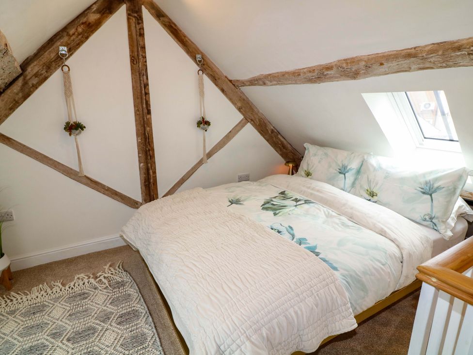 A bedroom with a bed and wooden beams at Jolly Cottage in Derby