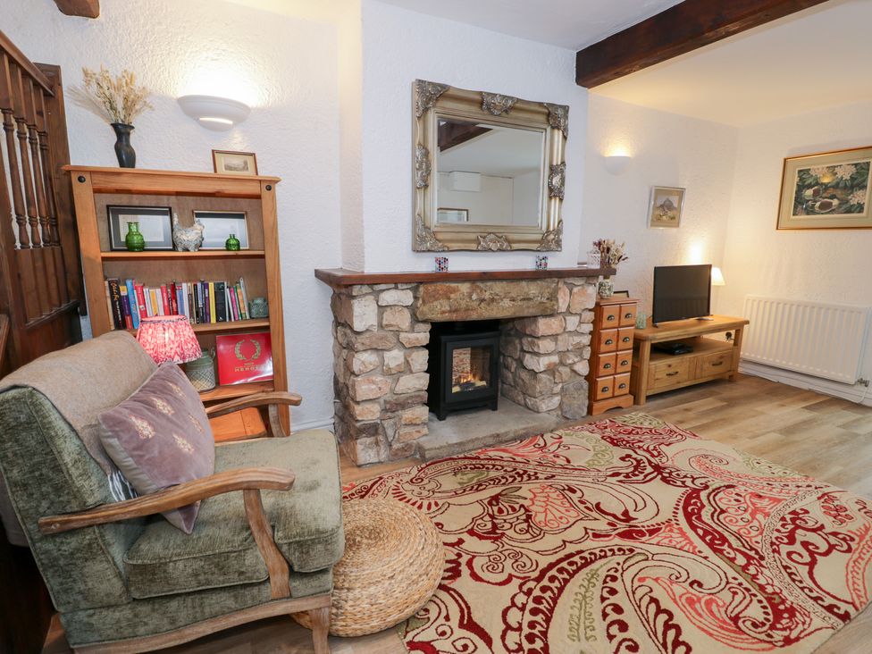 A living room with a sofa, bookshelves, and a fireplace at Ivy Cottage in Abergele