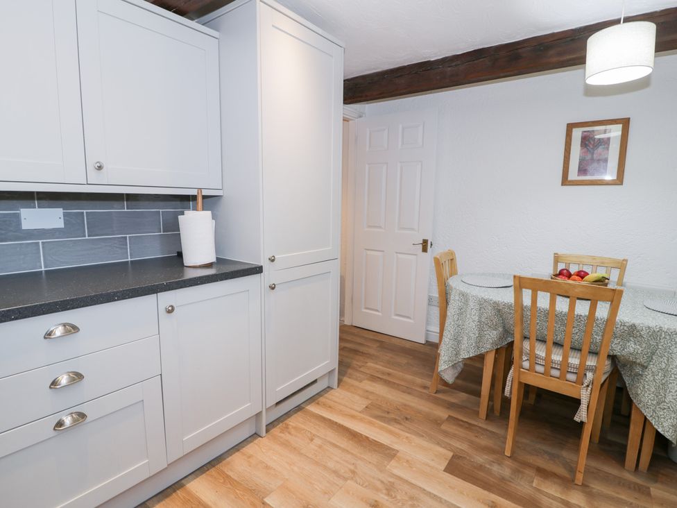 A kitchen with cabinets and a table with chairs at Ivy Cottage in Abergele
