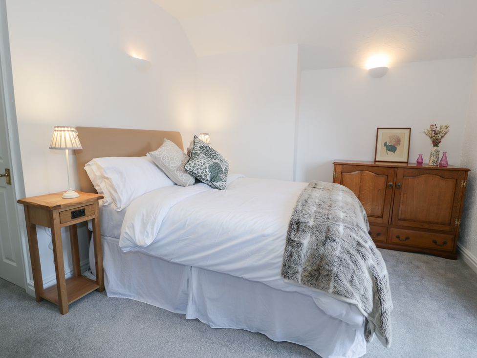 A bedroom with a bed and nightstand at Ivy Cottage in Abergele