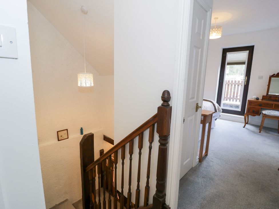 A hallway with a staircase and light fixture at Ivy Cottage in Abergele