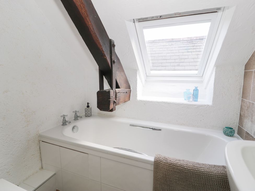A bathroom with a bathtub and window at Ivy Cottage in Abergele