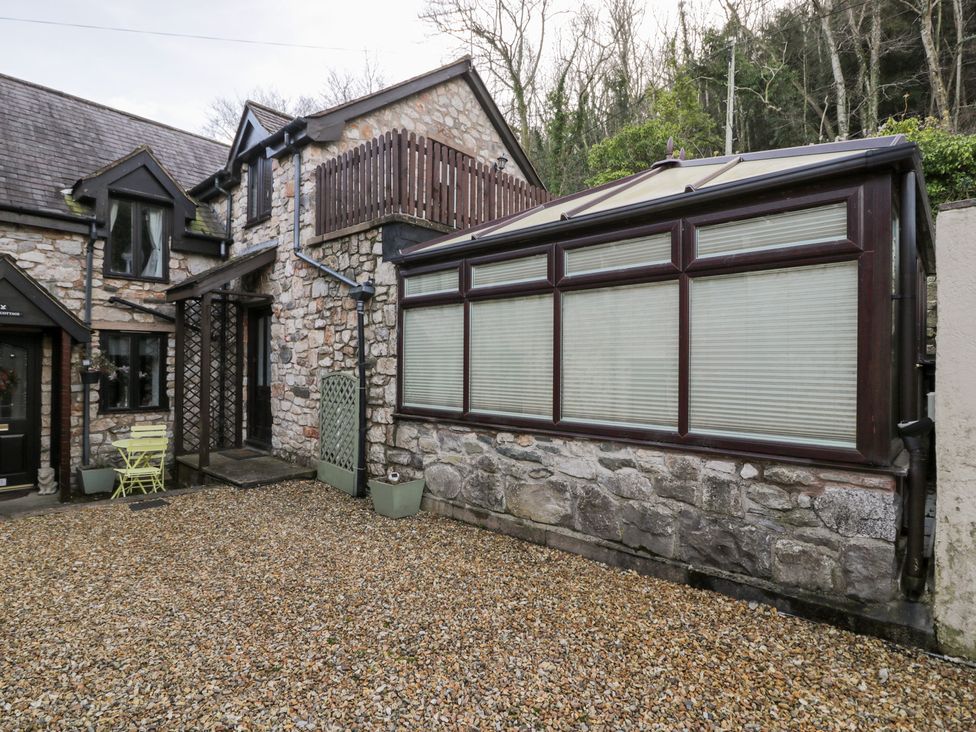 An outdoor area with stone walls and windows at Ivy Cottage in Abergele