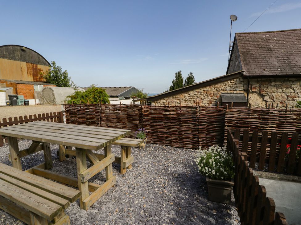 A garden with a wooden table and benches at Ivy Cottage in Abergele
