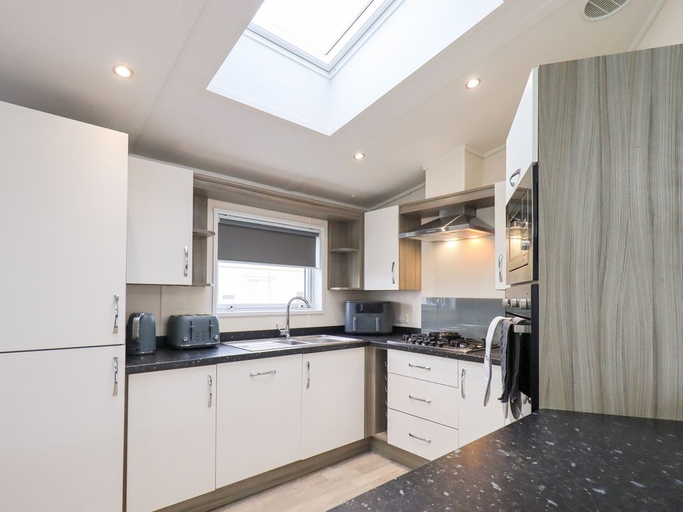 A kitchen with a sink stove and cabinets at Lily's Lodge in Morecambe