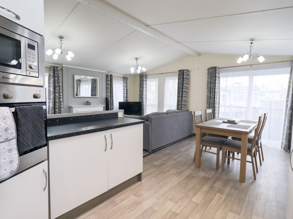 A living room with a kitchen area and dining table at Lily's Lodge in Morecambe