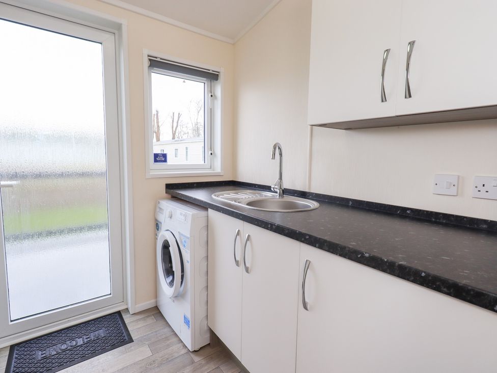 A laundry room with a washing machine and sink at Lily's Lodge in Morecambe