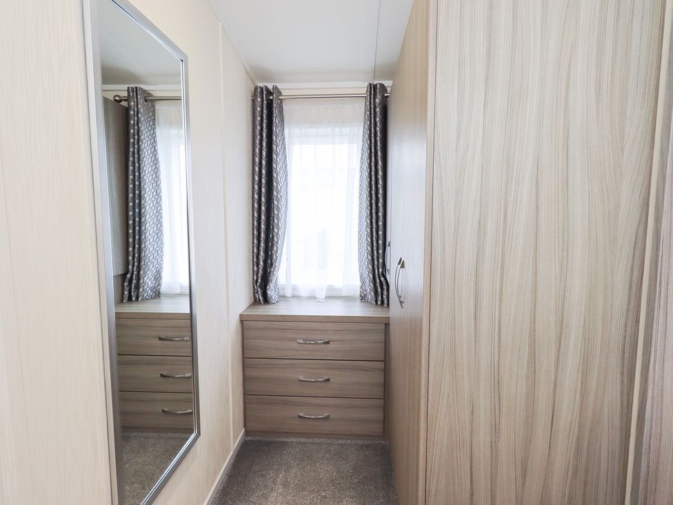 A bedroom with a mirror and dresser at Lily's Lodge in Morecambe
