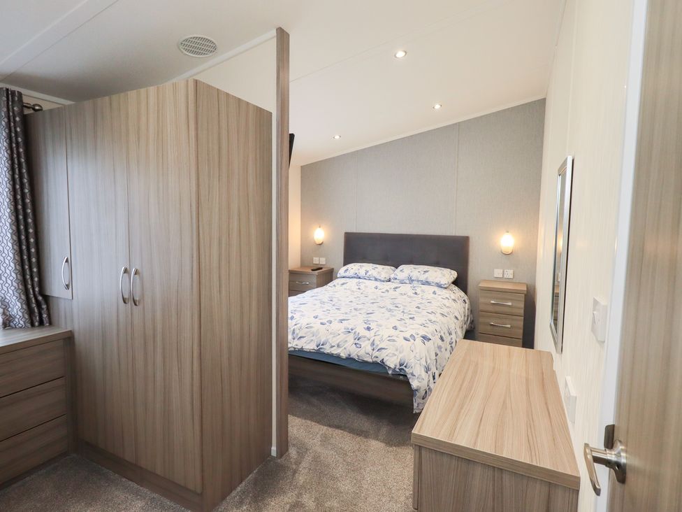 A bedroom with a bed and wardrobe at Lily's Lodge in Morecambe