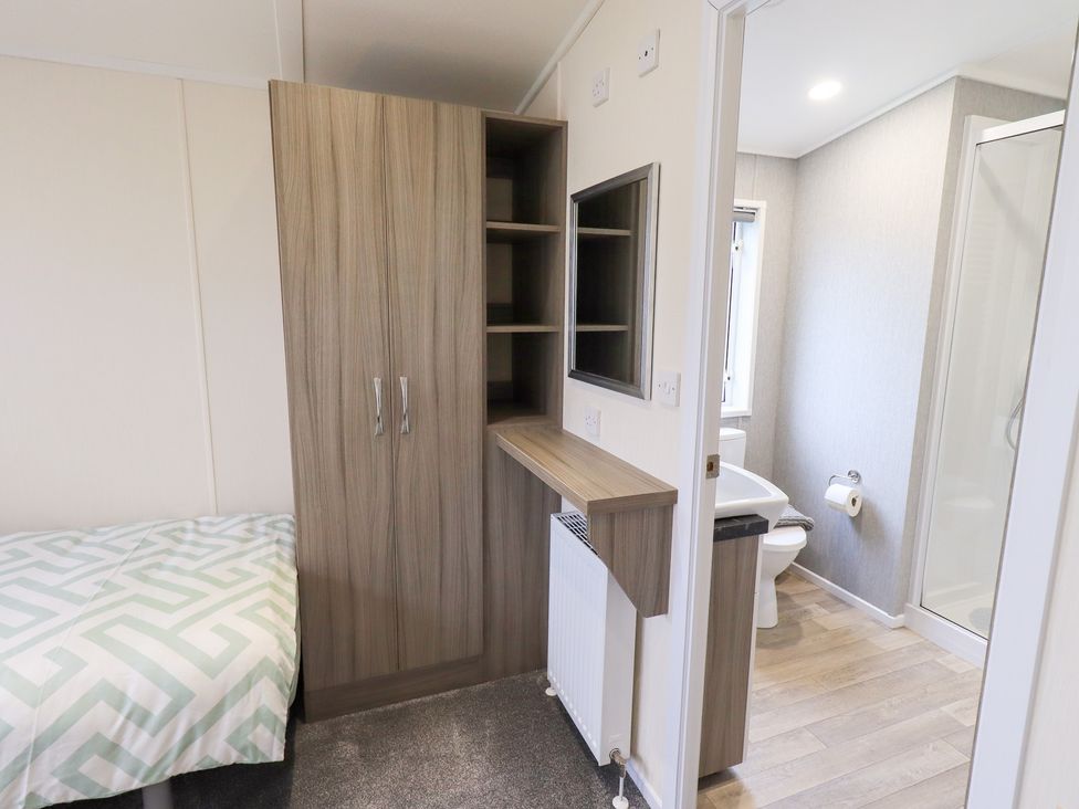 A bedroom with a bed, wardrobe, and attached bathroom at Lily's Lodge in Morecambe