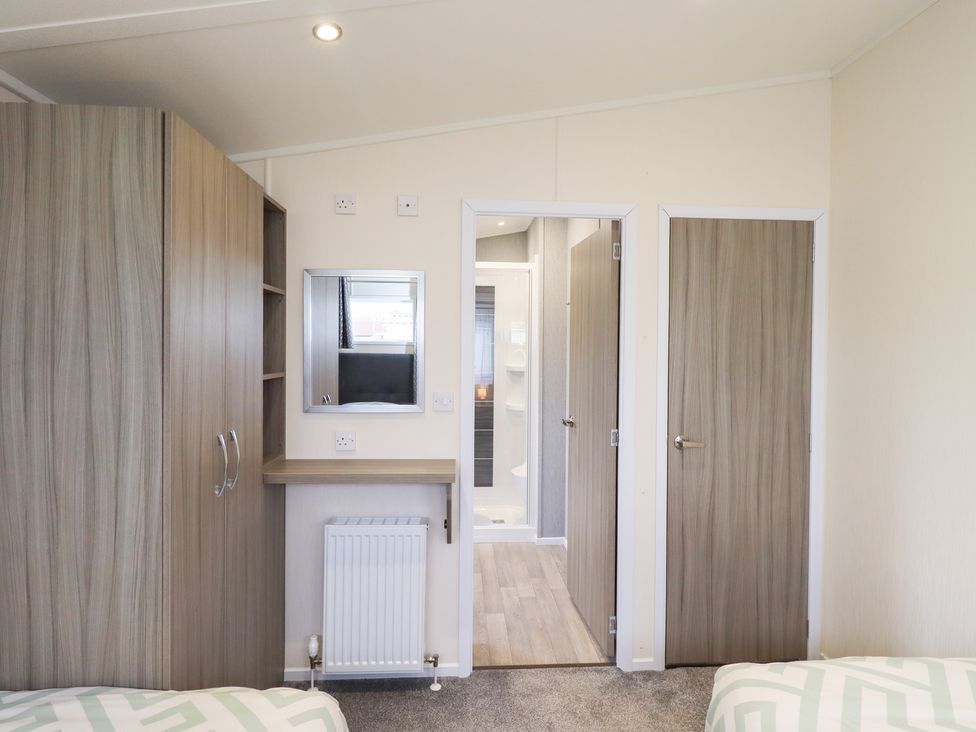 A bedroom with a wardrobe and a mirror at Lily's Lodge Morecambe