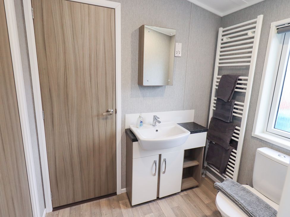 A bathroom with a sink, mirror, and toilet at Lily's Lodge Morecambe