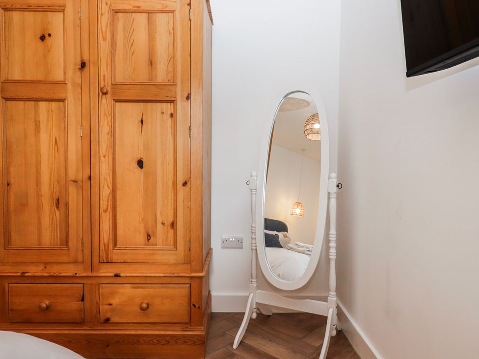 A bedroom with a wooden wardrobe and a standing mirror at Shamrock, Exeter