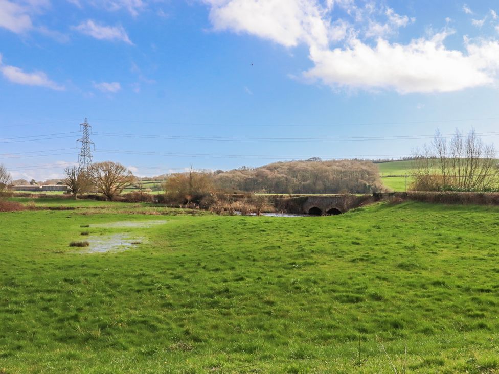 A river and bridge surrounded by grass and trees at Shamrock in Exeter