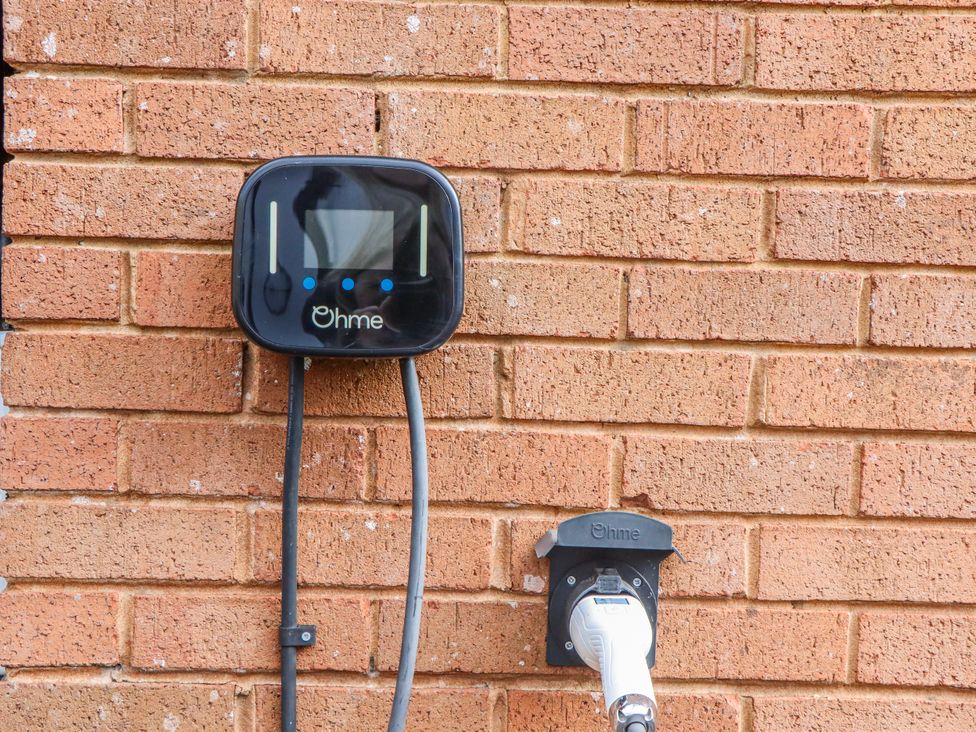 An electric vehicle charging unit mounted on a brick wall at Shamrock in Exeter