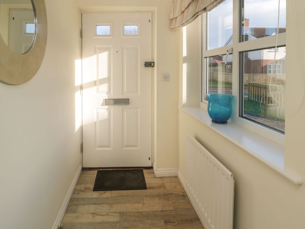 A hallway with a door and windows at Sandy Cove, Chathill
