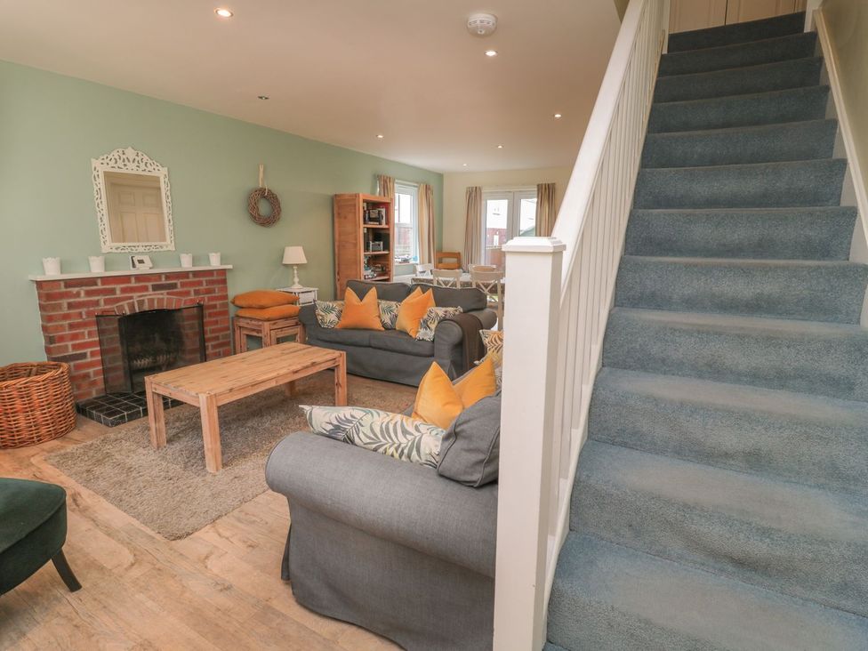 A living room with a fireplace and staircase at Sandy Cove in Chathill