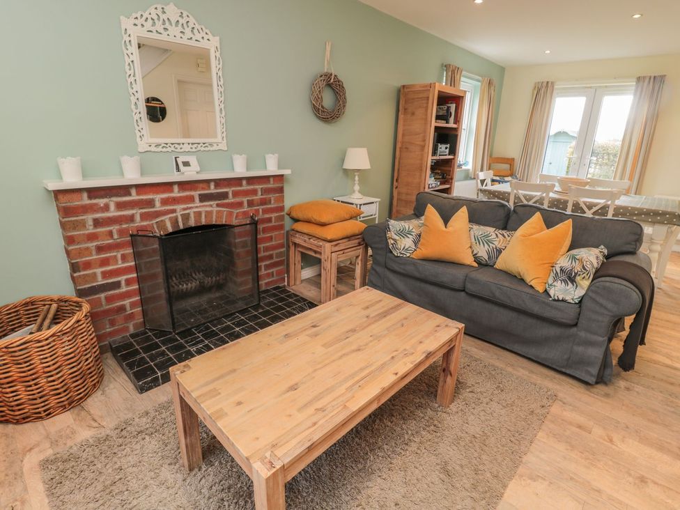 A living room with a fireplace and sofa at Sandy Cove in Chathill