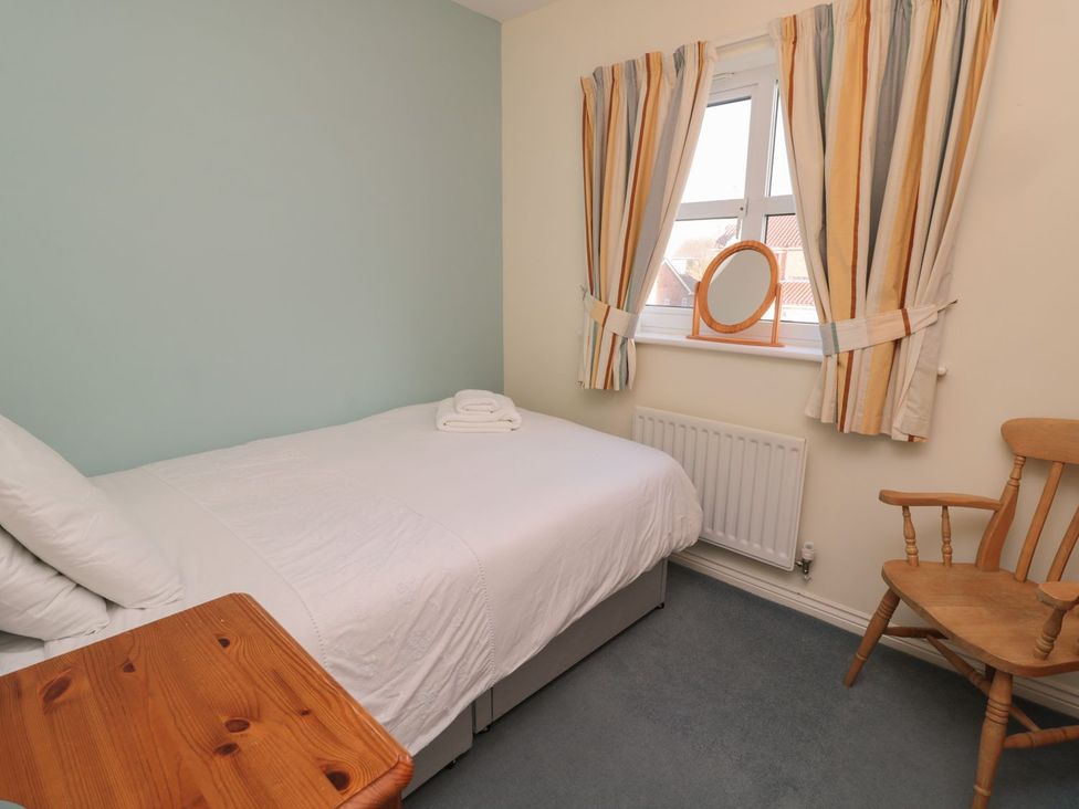 A bedroom with a bed and a chair at Sandy Cove in Chathill