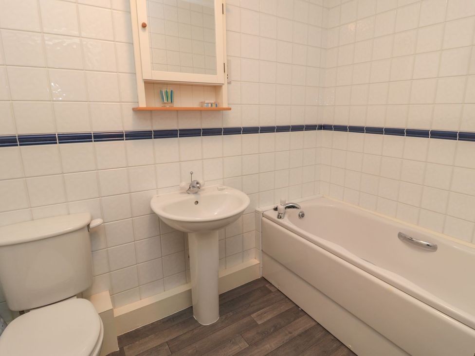 A bathroom with a toilet sink and bathtub at Sandy Cove in Chathill