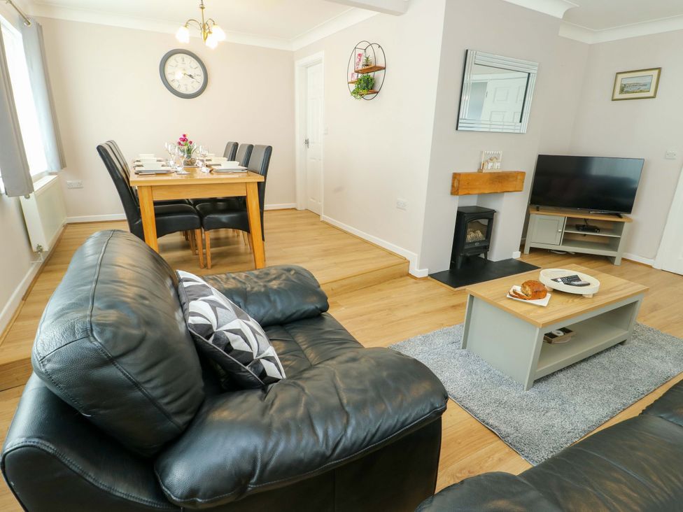 A living room with a sofa and dining area at Min Y Cae