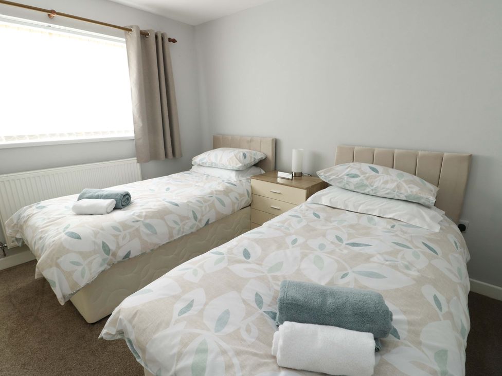 A bedroom with two single beds and a bedside table at Min Y Cae