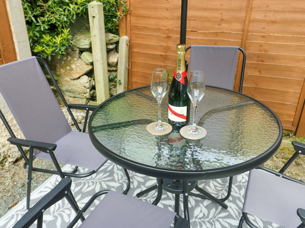 An outdoor seating area with a table and chairs, champagne bottle and glasses at Min Y Cae