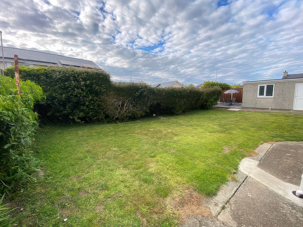 A garden with grass and hedges at Min Y Cae in Cemaes Bay