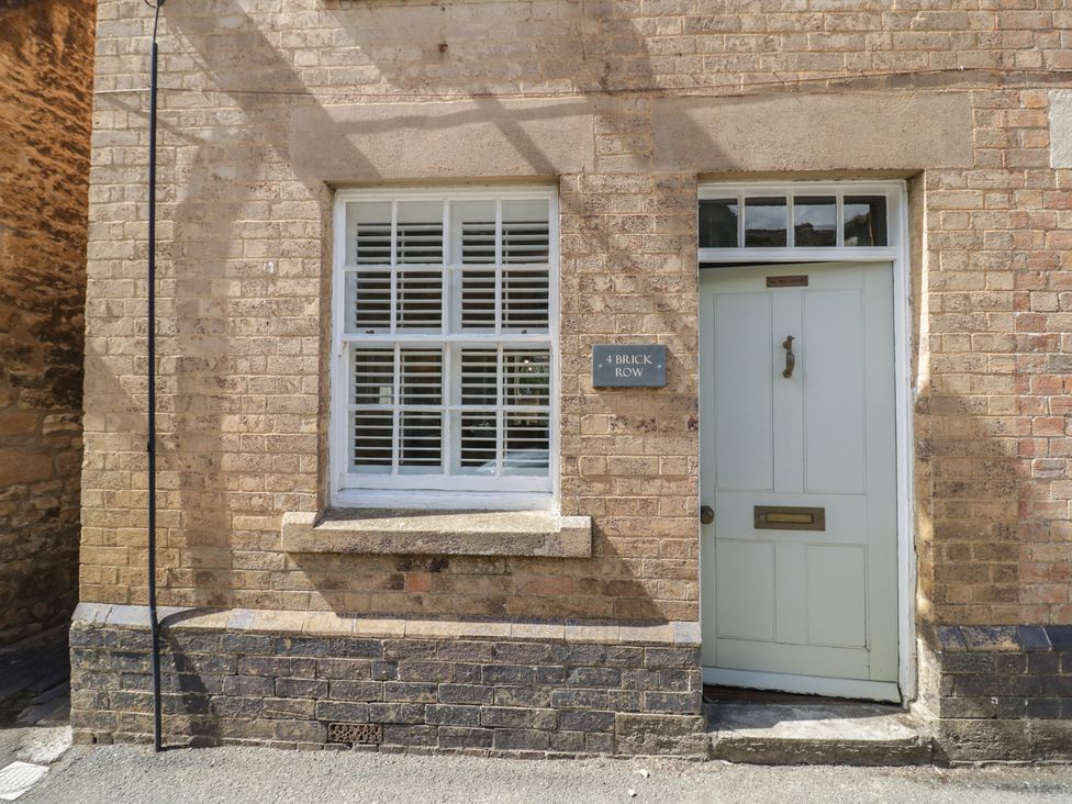 A door and window on a brick wall at Tea Tree Cottage in Chipping Campden