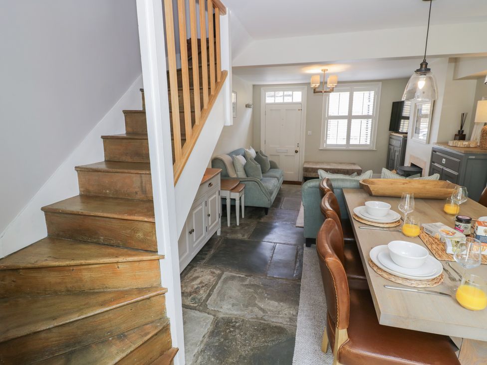 A living room with a dining area and staircase at Tea Tree Cottage in Chipping Campden