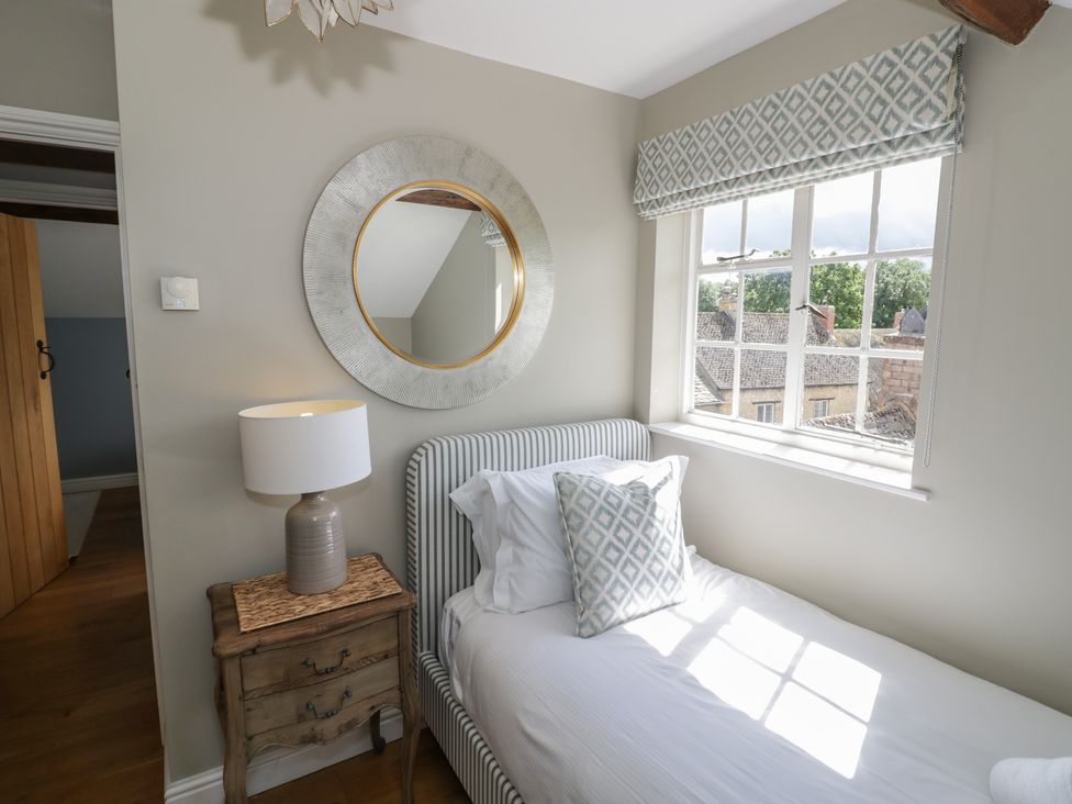A bedroom with a bed and a lamp at Tea Tree Cottage in Chipping Campden
