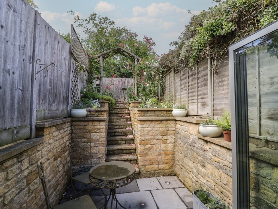 A garden with stone steps and planters at Tea Tree Cottage in Chipping Campden