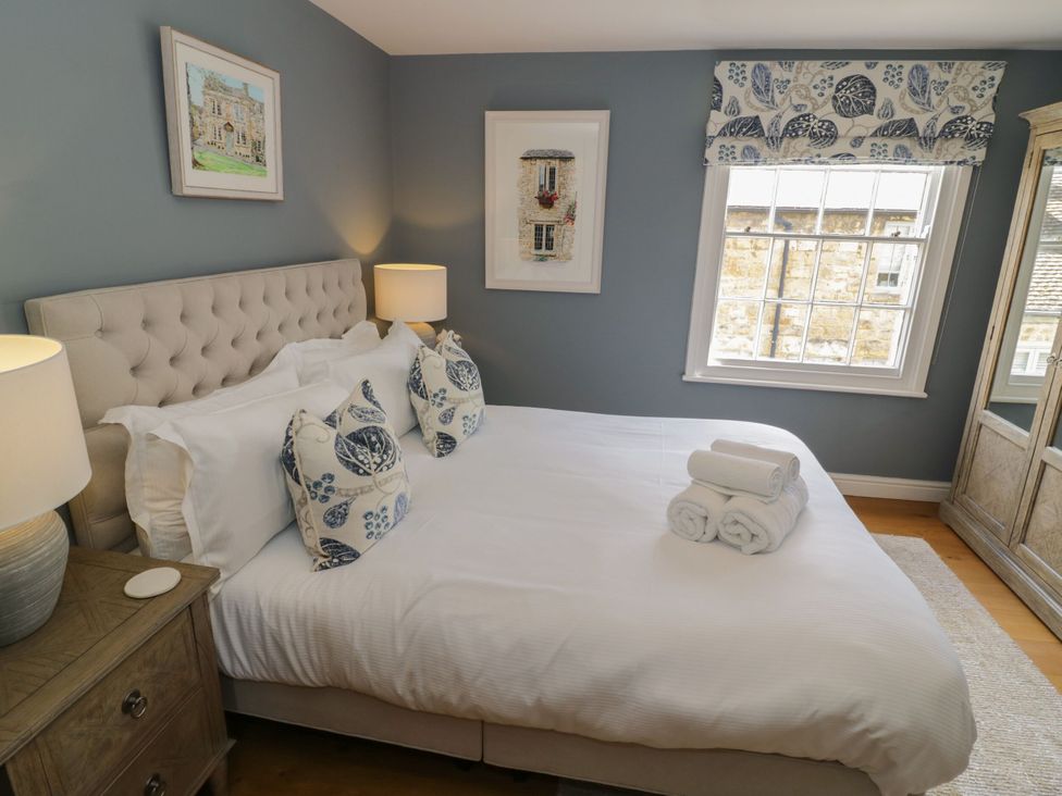 A bedroom with a bed and artwork at Tea Tree Cottage in Chipping Campden