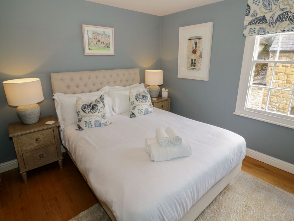 A bedroom with a bed and nightstand at Tea Tree Cottage in Chipping Campden