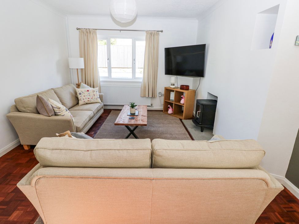 A living room with a sofa, coffee table, and television at Moonraker in Saundersfoot