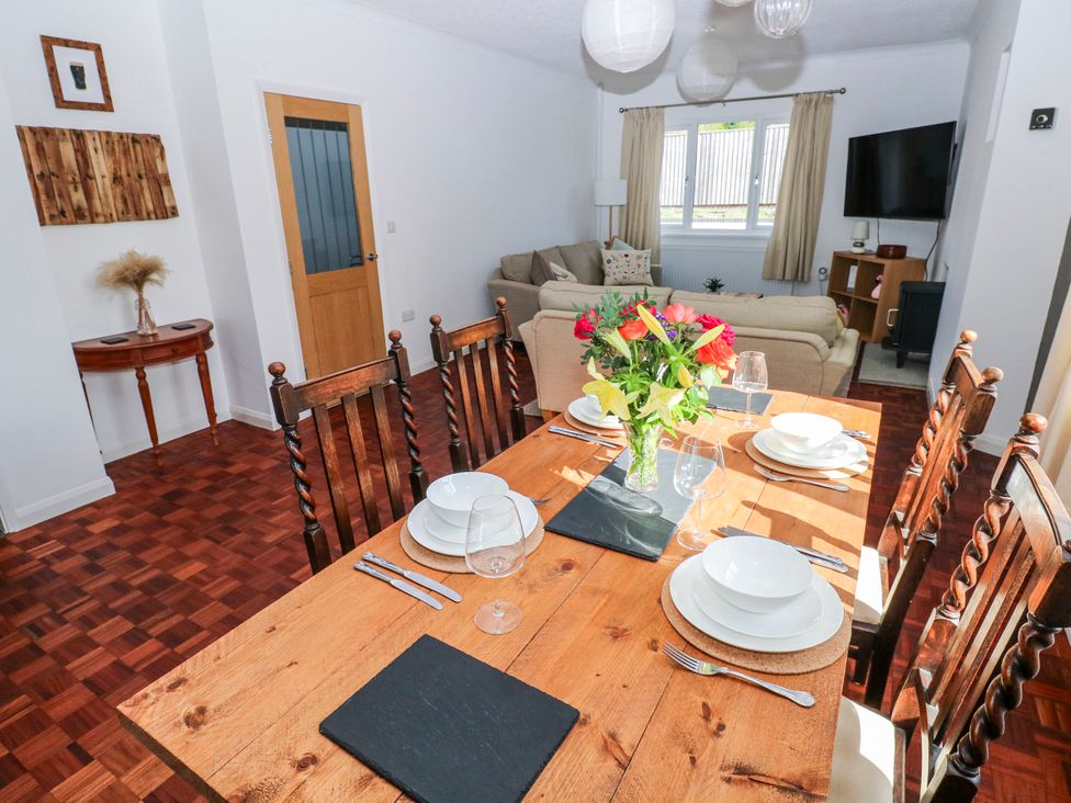 A dining room with a table set for meals and a sofa at Moonraker in Saundersfoot
